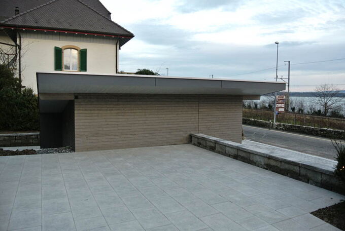 Garagenwand zu Gartensitzplatz mit grauer Holzschlaung verkleidet