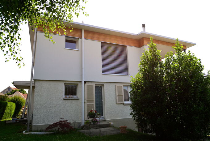 Fassadenansicht bei aufgestocktem Einfamilienhaus, OG mit modernen Fensterstoren, EG wurden die bestehenden Holzläden erhalten